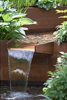 Corten steel water feature with pebbles, hosta and dragonfly - Chelsea Flower Show 2014. A Garden for First Touch at St. George's.  Designer: Patrick Collins.  Sponsore: St Georges Hospital and Medical School, Tendercare, Landscape Associates.  