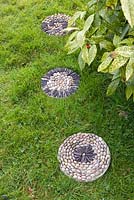 Pebble mosaic paving slabs in grass - stepping stones across lawn 