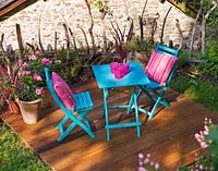 Wooden deck with blue table and chairs and pink cushions