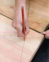 Constructing a circular deck - pencil marking out where to cut deck boards
