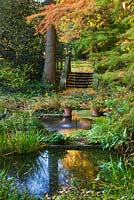 The water garden in autumn with stone steps and two shallow ponds with a single water jet. Saling Hall, Essex
