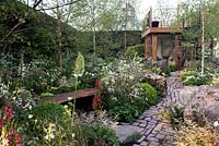 Vital Earth The Night Sky Garden. View to the wooden house with spiral straircase surrounded by Eremurus himalaicus,  Verbascum 'Petra', Aquilegiakristall, Aquilegia vulgarisvar. alba, Buxus.  