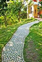Cobbled path through lawn leading to house. Designer: Jean-Laurent Felizia, France