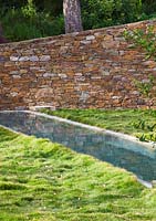 Lawn with swimming pool and rock wall. Designer: Jean-Laurent Felizia, France