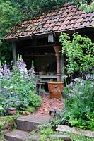 Potting shed with cottage style planting. Dial A Flight, RHS Chelsea Flower Show 2014. 