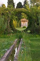 Water rill leads out through an arch hedge with view to folly. Les Confines, Provence, France