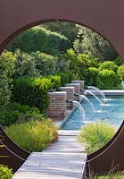 Modern contemporary garden - metal 'oculus' circle and swimming pool beyond with four brick water spouts
