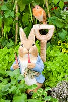 The Enchanting World of Peter Rabbit Herb Garden in the Grand Pavillion: Peter rabbit and robin on spade handle in the herb garden. 2014 RHS Chelsea Flower Show
