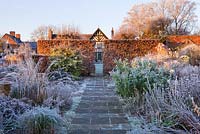 Wollerton Old Hall, Shropshire - Winter garden in frost - path to the house at dawn with clipped beech hedge and frosty borders 