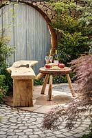Rustic wooden bench and table with food and wine with feature habitat wall behind, 'Shears and Chardonnay' RHS Malvern spring festival 2014 