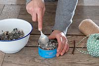 Bird food step by step - spooning mix of fat and seeds into old tin can