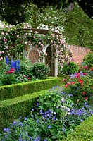 A classic English walled garden with box edged ornamental borders, climbing roses and wooden ornamental arbour. Seend, Wiltshire