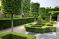 Italianate garden with simple box parterre and topiary trees. Agapanthus in pots. Trained ivy on wall.  Seend, Wiltshire