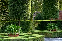Italianate topiary garden with stone gate pediment glimpsed between hedges. Seend, Wiltshire