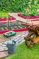 Raised beds with traditional wooden wheelbarrow and garden tools