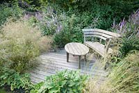 Decked seating area with bench and table surrounded by Veronicastrum virginicum 'Fascination'. Old Rectory, Batcombe, Somerset, UK
