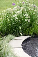 Luzula nivea' with Allium nex to a circular pool - Levels': A Garden, Come Rain or Shine, RHS Malvern Spring Festival 2014