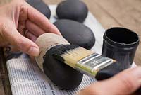 Painting pebbles with a black paint.