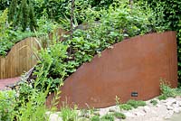 Title: Paradigme. Rust iron oval shaped tubs filled with plants.