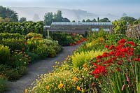 Mixed borders with glasshouse in background, West Dean walled garden, Sussex 