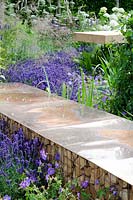 Gabions filled with split logs, topped with copper for seating surrounded by Lavandula, Geranium - Vestra Wealth's Vista Garden, RHS Hampton Court Palace Flower Show 2014 - Design: Paul Martin - Sponsor: Vestra Wealth