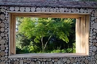 Log cabin window with view through to Acer palmatum dissectum 'Seiryu' - Green is the Colour, RHS Hampton Court Palace Flower Show 2014 - Design: Elinor Scarth 