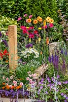 1970s and modern planting including Dianthus 'Doris' and Geranium 'Rozanne' with wooden post marking the eara, The NSPCC Legacy Garden, RHS Hampton Court Flower Show 2014