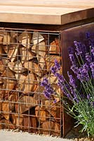 Lavandula 'Hidcote' by copper and logs seating platform - RHS Hampton Court Palace Flower Show 2014 -  Vestra Wealth's Vista.  Designer: Paul Martin. Sponsor: Vestra Wealth.  
