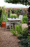 Small al fresco dining area with verbascum, clematis and brick wall