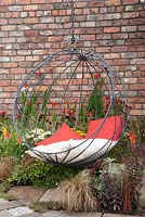 ndustrial Transitions - swing seat in outdoor living area planting of Crocosmia 'Lucifer' Helenium and red hot pokers 