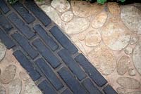 Sliced cobbles and dark tile insets in a path