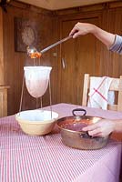 Making rosehip jam. Strain the boiled mixture through a muslin