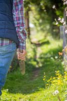 Woman leaving allotment carrying hand trowel