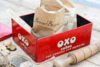 Saved garden seed in paper packets in OXO tin, with wooden dibber, ruler and garden items