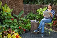 Woman reading a newspaper, relaxing in her garden retreat