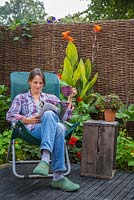 Woman reading a magazine, relaxing in her garden retreat