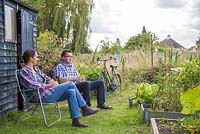 Man and woman sat in deck chairs at an allotment plot