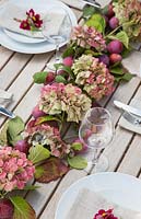Table place setting decorations with hydrangea, cosmos bipinnatus 'Antiquity' and plums - Prunus domestica 'Victoria'