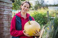 Proud woman holding harvested Pumpkin Hundred Weight