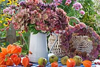 Jug of Hydrangea seedheads, wreath, Physalis and basket of harvested pears and apples.