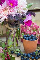 Floral display of Cosmos, Kale and Chrysanthemum 'Bloom Allouise Pink' in a glass jar, accompanied with Prunus spinosa - Sloe berries, Hydrangea and hawthorn