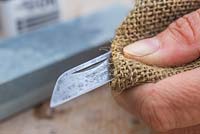 Using a cloth to give the knife a good clean, removing any oil and dirt - maintaining garden knife 