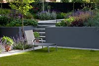 Sun lounger next to grey retaining walls, lounger, Flowerbeds and container planting 