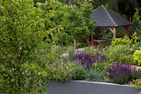 View to covered dining area, retaining walls with mixed planting and trees - Pyrus 'Chanticleer'