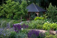 View to covered dining area, mixed flowerbeds and trees -  Pyrus 'Chanticleer'