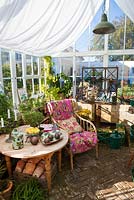 Wicker chair, wooden table, seating area in greenhouse 