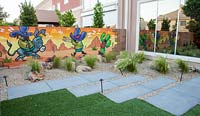 Garden surrounded by wall murals. Plants include Stipa tenuissima  