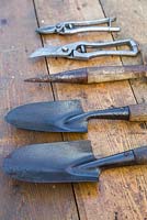 Collection of vintage garden tools on a wooden surface. Secateurs, Seed Dibber and Hand Trowels