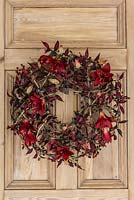Everlasting Christmas wreath. Silk flowers, foliage and artificial berries are secured onto a circular base of entwined stems.