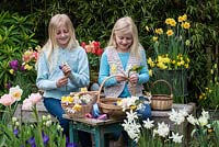 Mother's day posie in April. Sisters arranging the flowers, chosen from Pink Clematis armandii 'Apple Blossom', white amelanchier, daffodils, grape hyacinths, snowflakes, hellebores, lungwort, pear blossom and pink tulips.